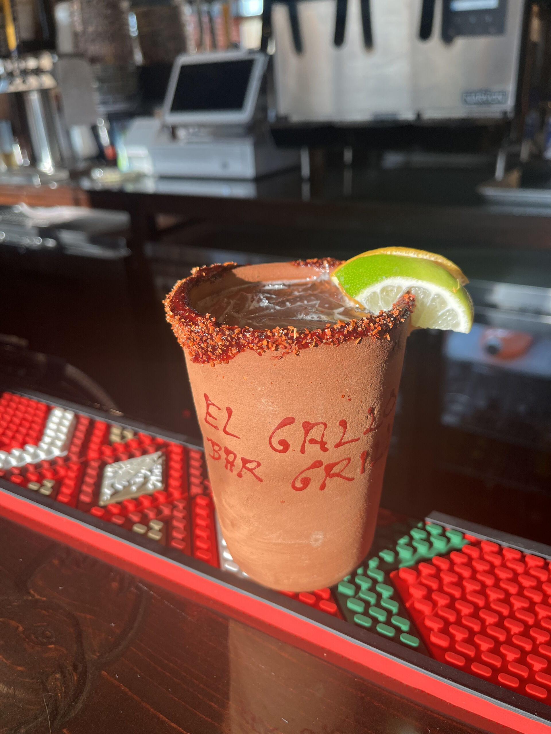 Close up on a margarita in a clay cup, garnished with a lime wedge.